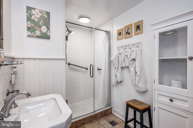 bathroom featuring a shower with door and sink