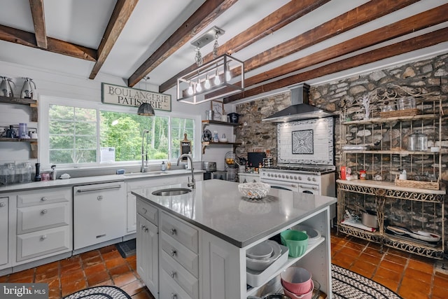 kitchen featuring sink, a center island with sink, dishwasher, beam ceiling, and wall chimney range hood