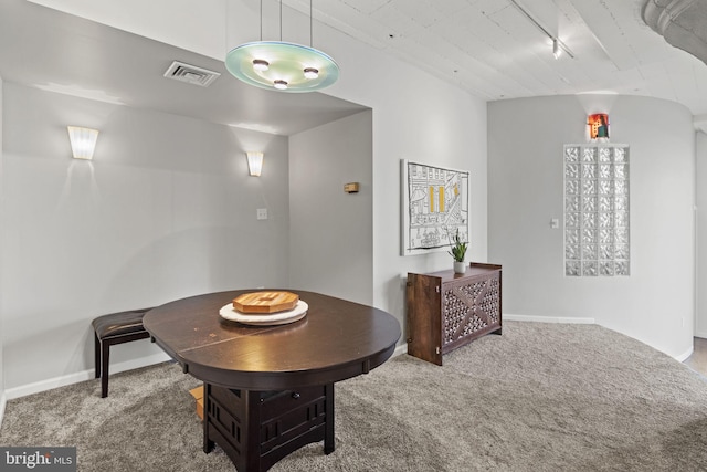 dining area with rail lighting and carpet flooring