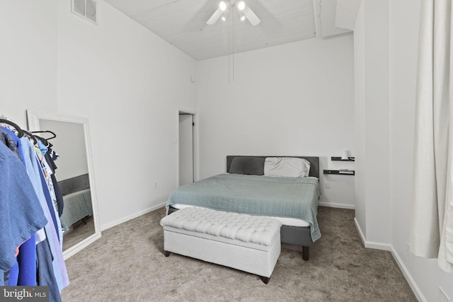 carpeted bedroom with ceiling fan and a high ceiling