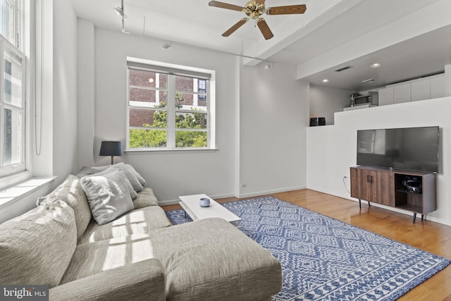 living room with ceiling fan, light hardwood / wood-style flooring, and beamed ceiling