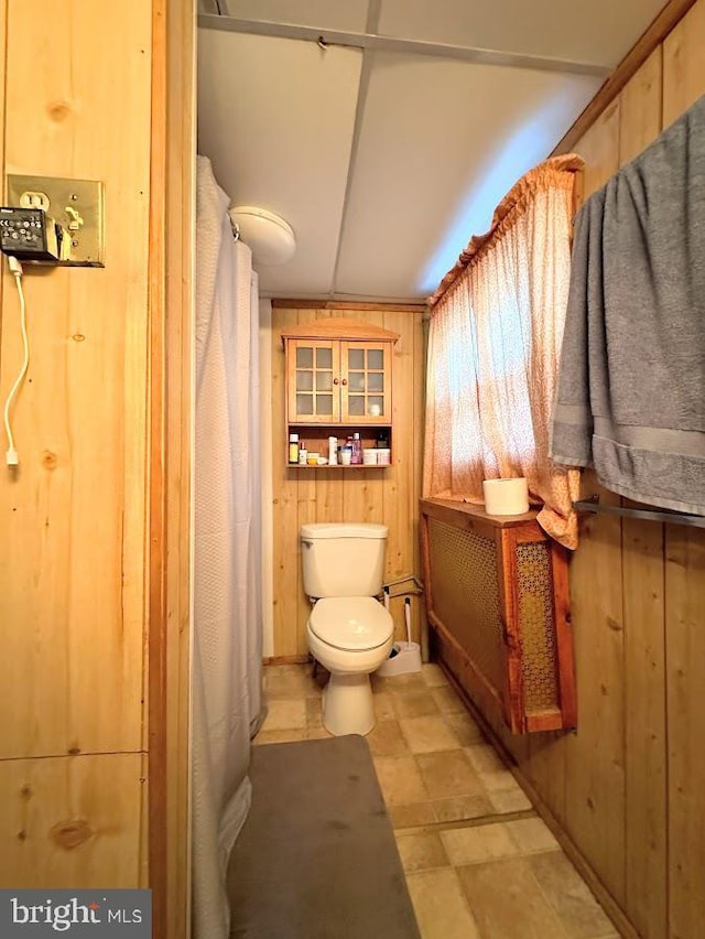 bathroom featuring wood walls and toilet