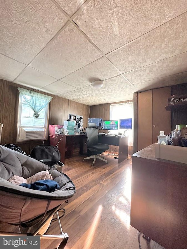 interior space featuring hardwood / wood-style floors, a paneled ceiling, and wood walls