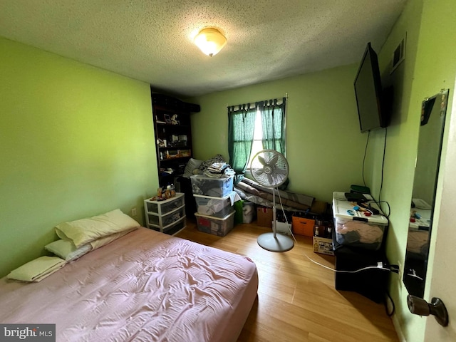 bedroom with light wood-type flooring and a textured ceiling