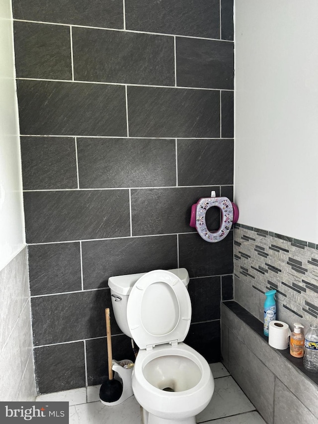 bathroom featuring toilet and tile walls