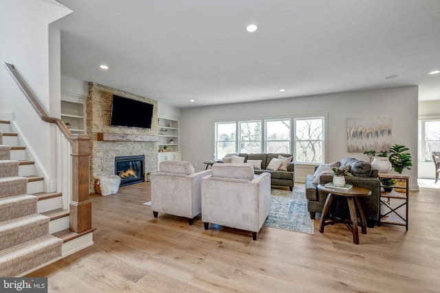 living room featuring built in features, a fireplace, and light wood-type flooring