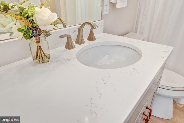 bathroom with hardwood / wood-style flooring, toilet, and vanity