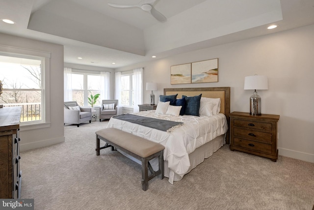 bedroom featuring light colored carpet, a raised ceiling, and ceiling fan