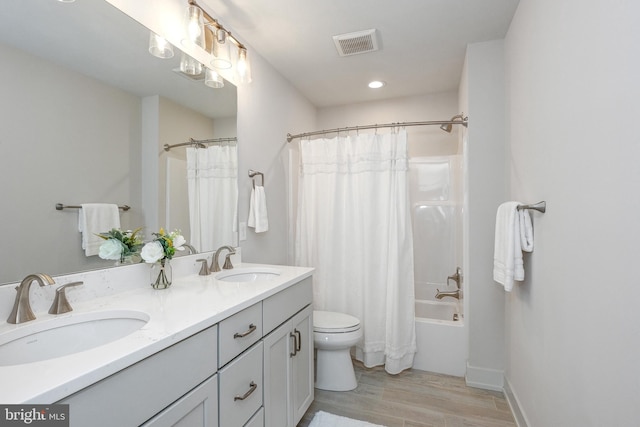 full bathroom with hardwood / wood-style flooring, dual vanity, shower / bathtub combination with curtain, and toilet