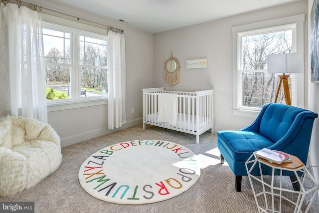 carpeted bedroom with a crib and multiple windows