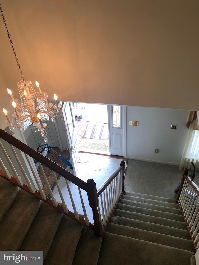 stairs featuring carpet flooring and an inviting chandelier