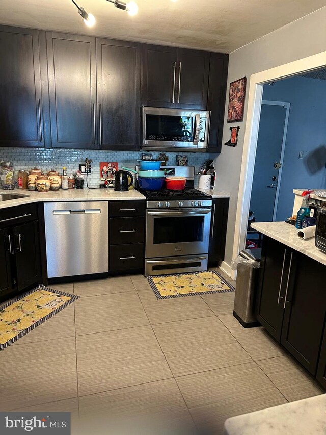 kitchen with light tile patterned flooring, backsplash, and appliances with stainless steel finishes