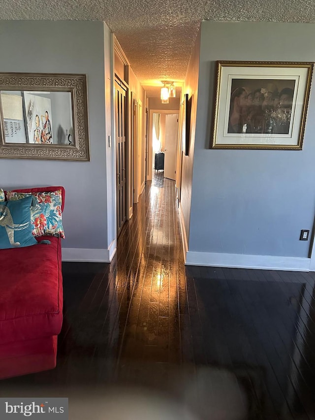 corridor featuring a textured ceiling and dark hardwood / wood-style floors