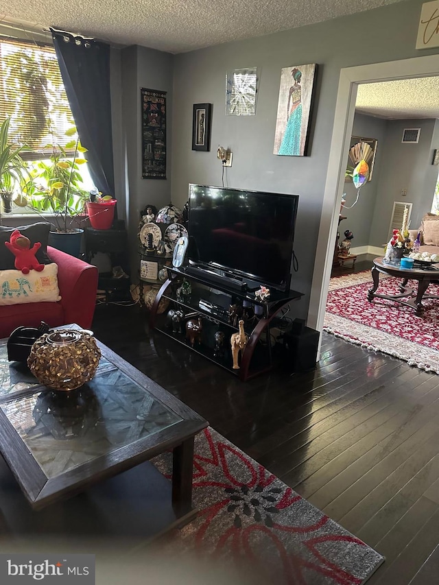 living room with a textured ceiling and dark wood-type flooring