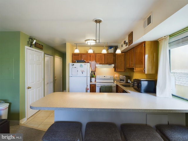 kitchen featuring white appliances, visible vents, a peninsula, light countertops, and under cabinet range hood