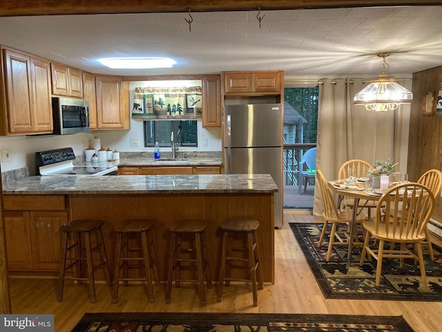 kitchen featuring sink, dark stone countertops, a kitchen breakfast bar, light hardwood / wood-style floors, and stainless steel appliances