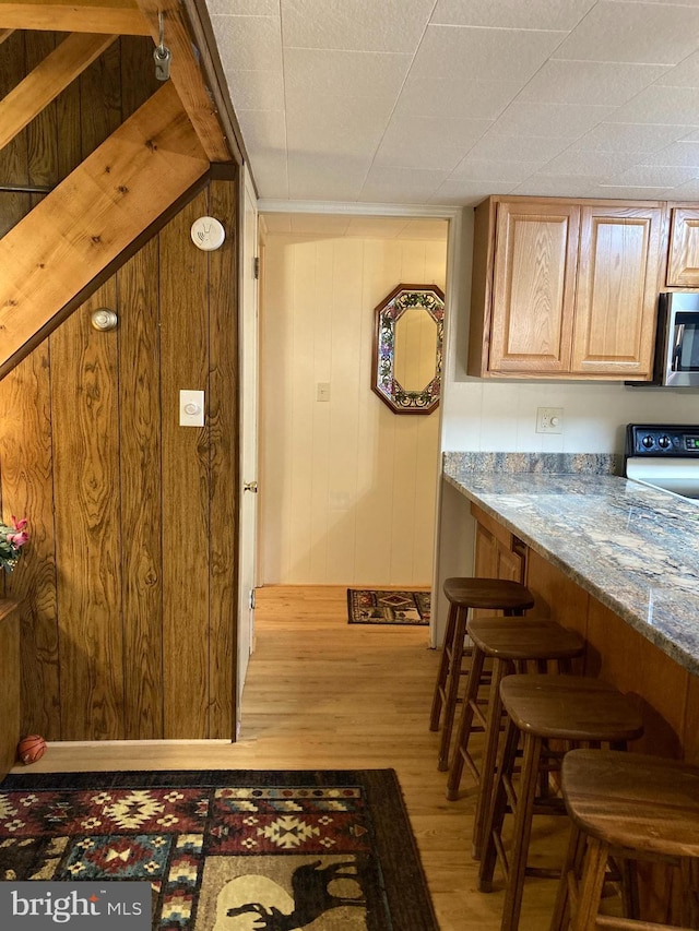 kitchen with hardwood / wood-style flooring, wood walls, light stone countertops, and range with electric cooktop