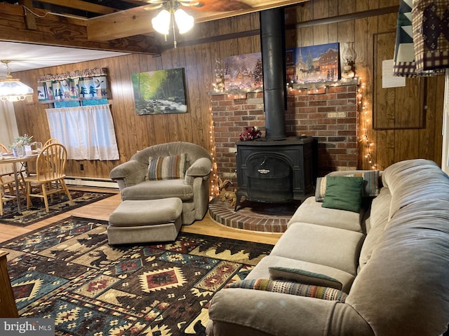 living room featuring beamed ceiling, a wood stove, wood walls, a baseboard heating unit, and wood-type flooring