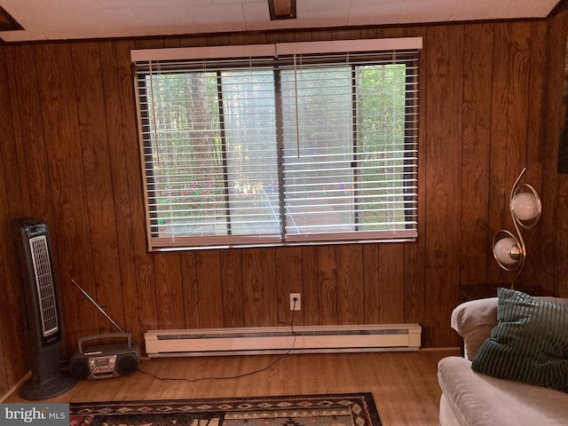 sitting room featuring a baseboard radiator, plenty of natural light, and wooden walls