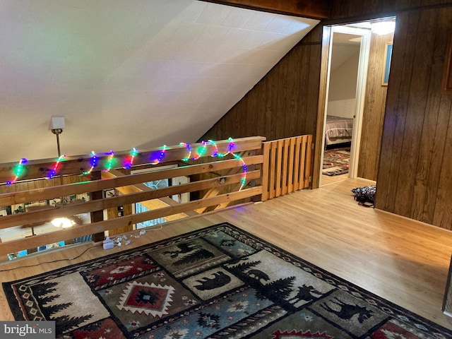 interior space featuring hardwood / wood-style floors, vaulted ceiling, and wood walls