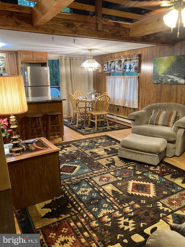 living room featuring light hardwood / wood-style floors, wood walls, beamed ceiling, and baseboard heating