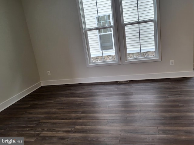 empty room featuring dark wood-type flooring and plenty of natural light