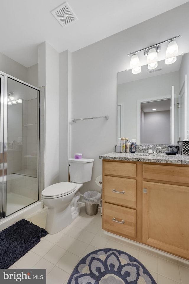 bathroom featuring a shower with shower door, vanity, tile patterned flooring, and toilet