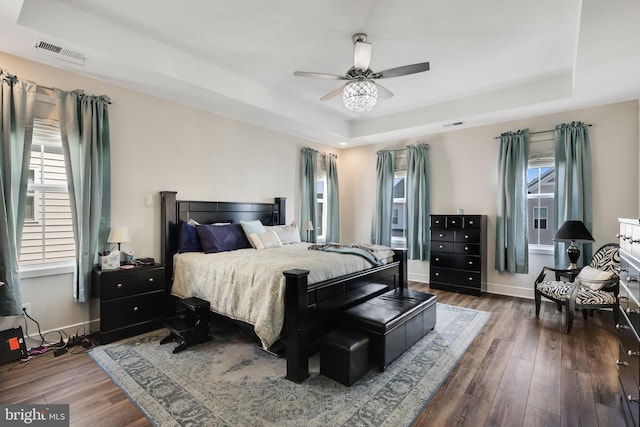 bedroom with ceiling fan, hardwood / wood-style floors, and a tray ceiling