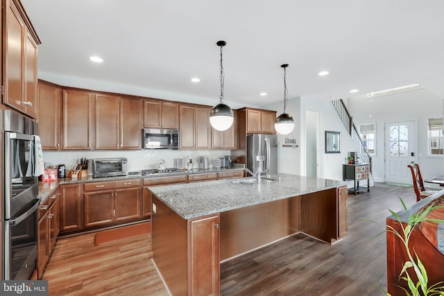 kitchen featuring a kitchen island, appliances with stainless steel finishes, light stone countertops, and wood-type flooring