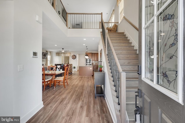 foyer featuring a high ceiling, ceiling fan, hardwood / wood-style flooring, and a healthy amount of sunlight