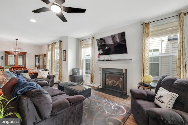 living room with ceiling fan with notable chandelier and wood-type flooring