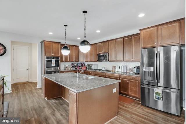 kitchen featuring light hardwood / wood-style floors, appliances with stainless steel finishes, sink, and a kitchen island with sink