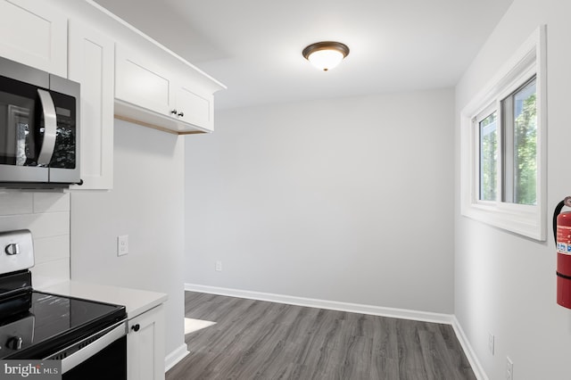 kitchen with white cabinets, wood-type flooring, tasteful backsplash, and electric stove