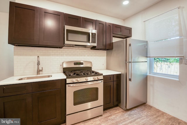 kitchen with dark brown cabinetry, stainless steel appliances, tasteful backsplash, and sink