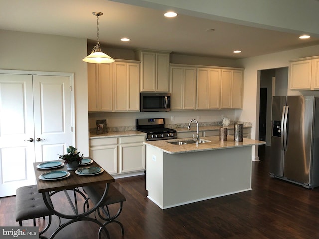 kitchen featuring decorative light fixtures, an island with sink, dark hardwood / wood-style flooring, appliances with stainless steel finishes, and sink