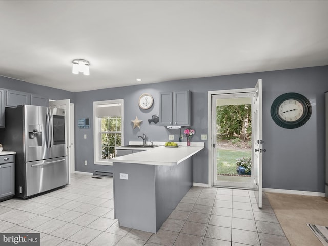 kitchen featuring stainless steel fridge with ice dispenser, kitchen peninsula, gray cabinets, a breakfast bar, and sink