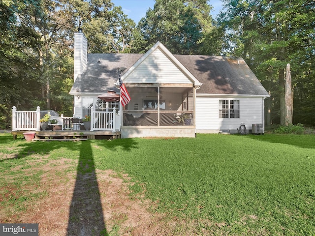 back of property featuring a deck, a sunroom, a yard, and central AC