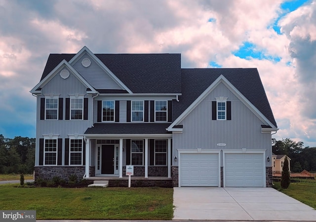 view of front of property featuring a lawn, a garage, and a porch