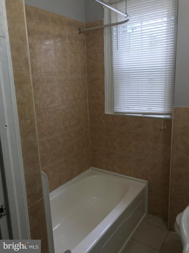 bathroom with tiled shower / bath combo, tile patterned floors, and toilet