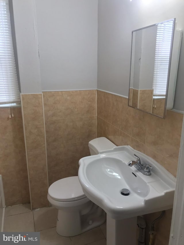 bathroom featuring sink, toilet, tile patterned flooring, and tile walls