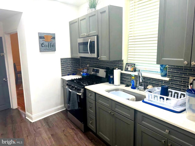 kitchen featuring appliances with stainless steel finishes, backsplash, gray cabinets, and sink