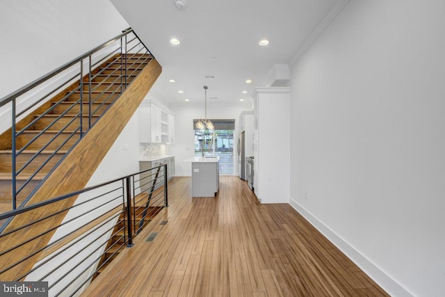 hallway with light hardwood / wood-style floors and ornamental molding