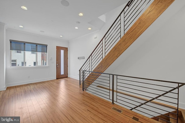 entryway featuring light wood-type flooring and ornamental molding