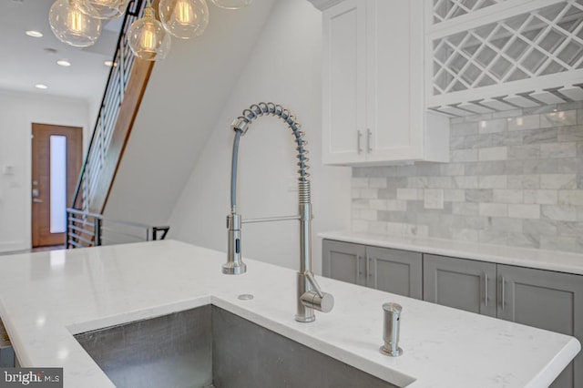 interior details featuring gray cabinetry, sink, tasteful backsplash, decorative light fixtures, and white cabinets