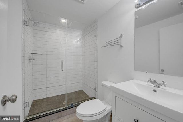 bathroom featuring tile patterned floors, vanity, a shower with shower door, and toilet