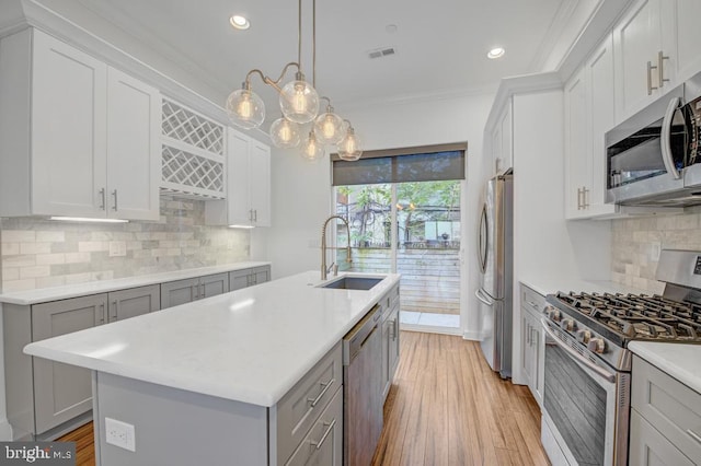 kitchen featuring sink, stainless steel appliances, an island with sink, gray cabinets, and ornamental molding