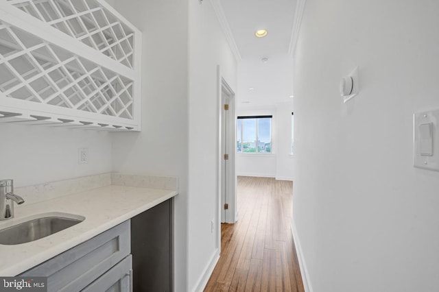 bar featuring hardwood / wood-style flooring, ornamental molding, and sink