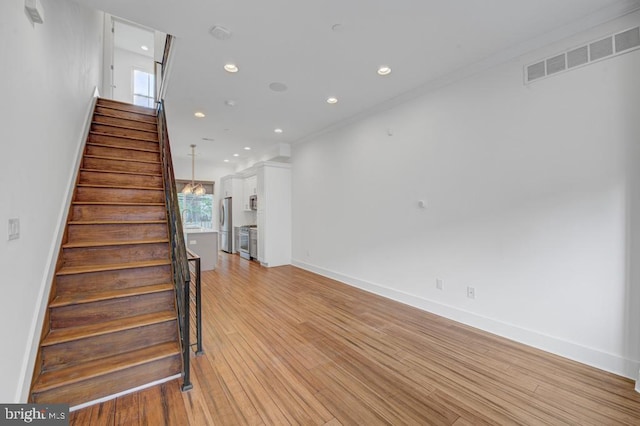 stairway featuring hardwood / wood-style floors, crown molding, and sink