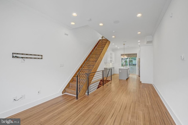 hallway featuring an inviting chandelier, light hardwood / wood-style floors, and ornamental molding