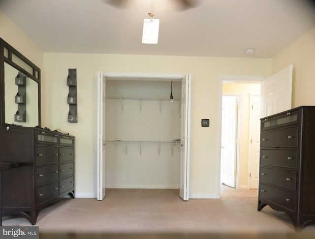 bedroom featuring ceiling fan, light colored carpet, and a closet